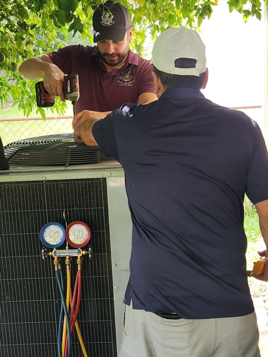 Michael Lopez and Lead Technician Jose Lopez of Who-Dat servicing an AC condensing unit with HVAC manifold gauges