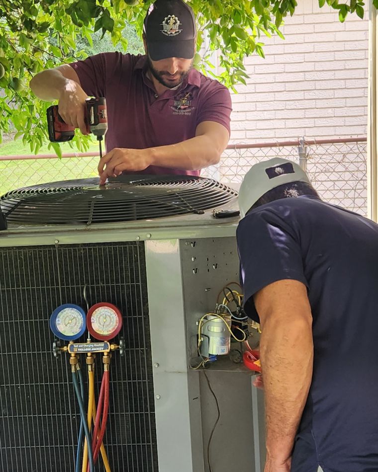 Michael and Jose Lopez of Who-Dat servicing an outdoor AC condensing unit with HVAC manifold gauges