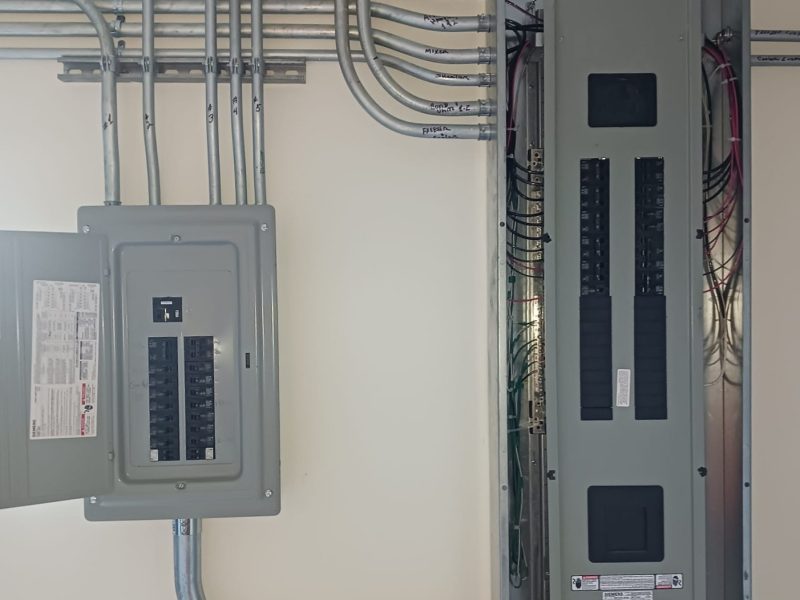 Two new electrical panels with neatly labeled conduit runs on an interior wall