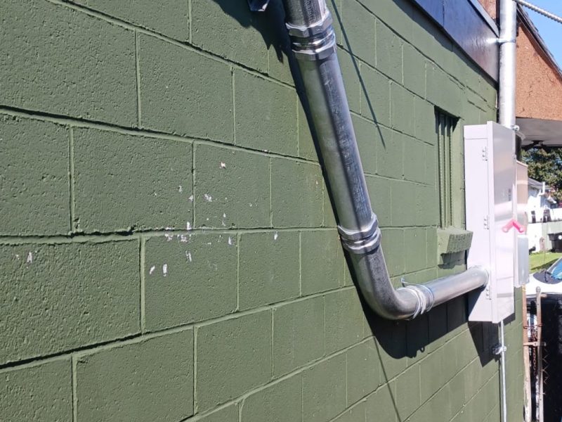 Rigid steel conduit service run and new panel installed on a painted block wall